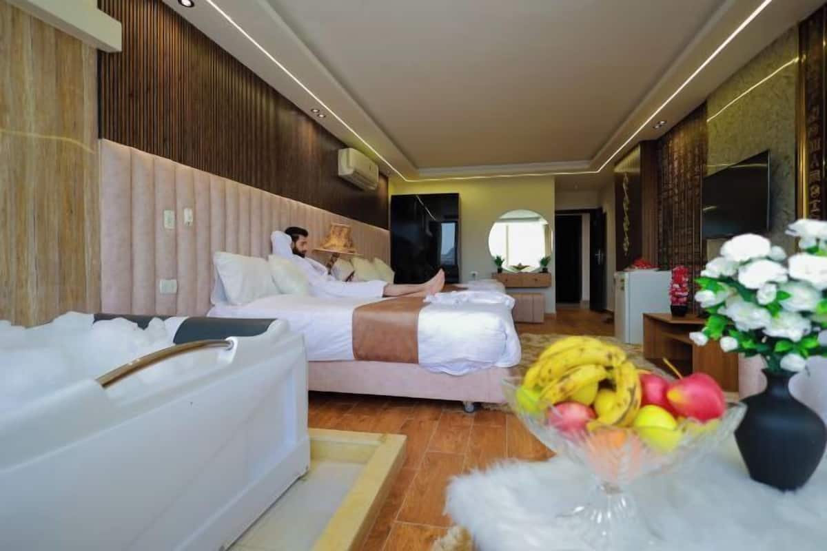 Habitació d'hotel moderna amb un llit gran, una banyera i un plat de fruita.