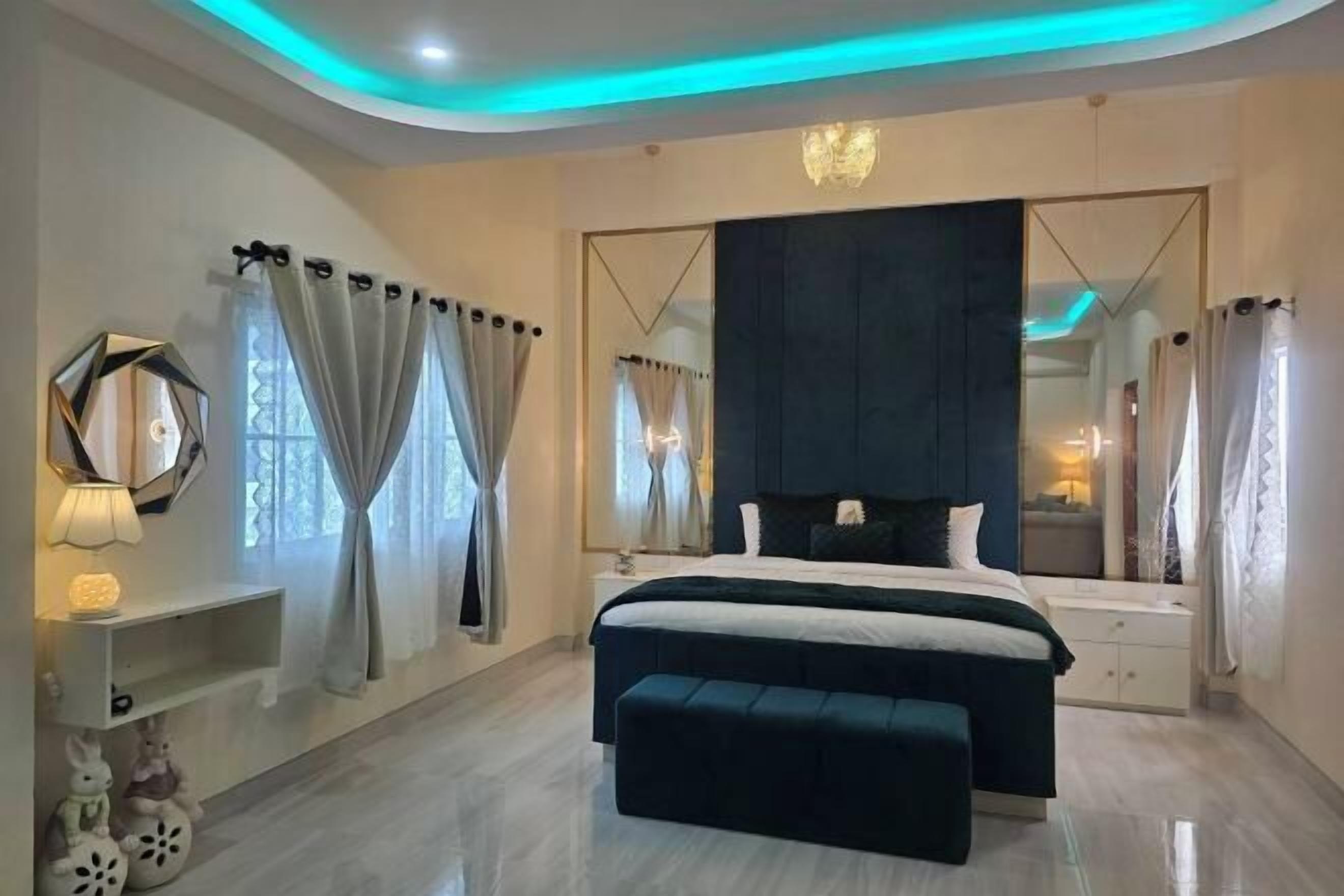 Un dormitorio moderno con una cama grande, una mesita de noche, un espejo y un banco.