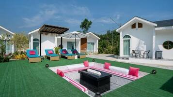 A modern outdoor lounge area with multiple lounge chairs and a fire pit.