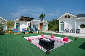 Eine moderne Lounge-Bereich im Freien mit mehreren Liegestühlen und einem Feuerkorb.