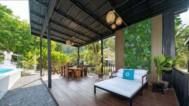 Ein überdachter Außenbereich mit Bett, Tisch und kleinem Pool.