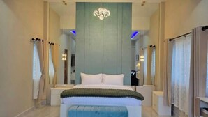 Ein modernes Schlafzimmer mit einem großen Bett, Nachttischen, einer Bank und einer außergewöhnlichen Deckenleuchte.