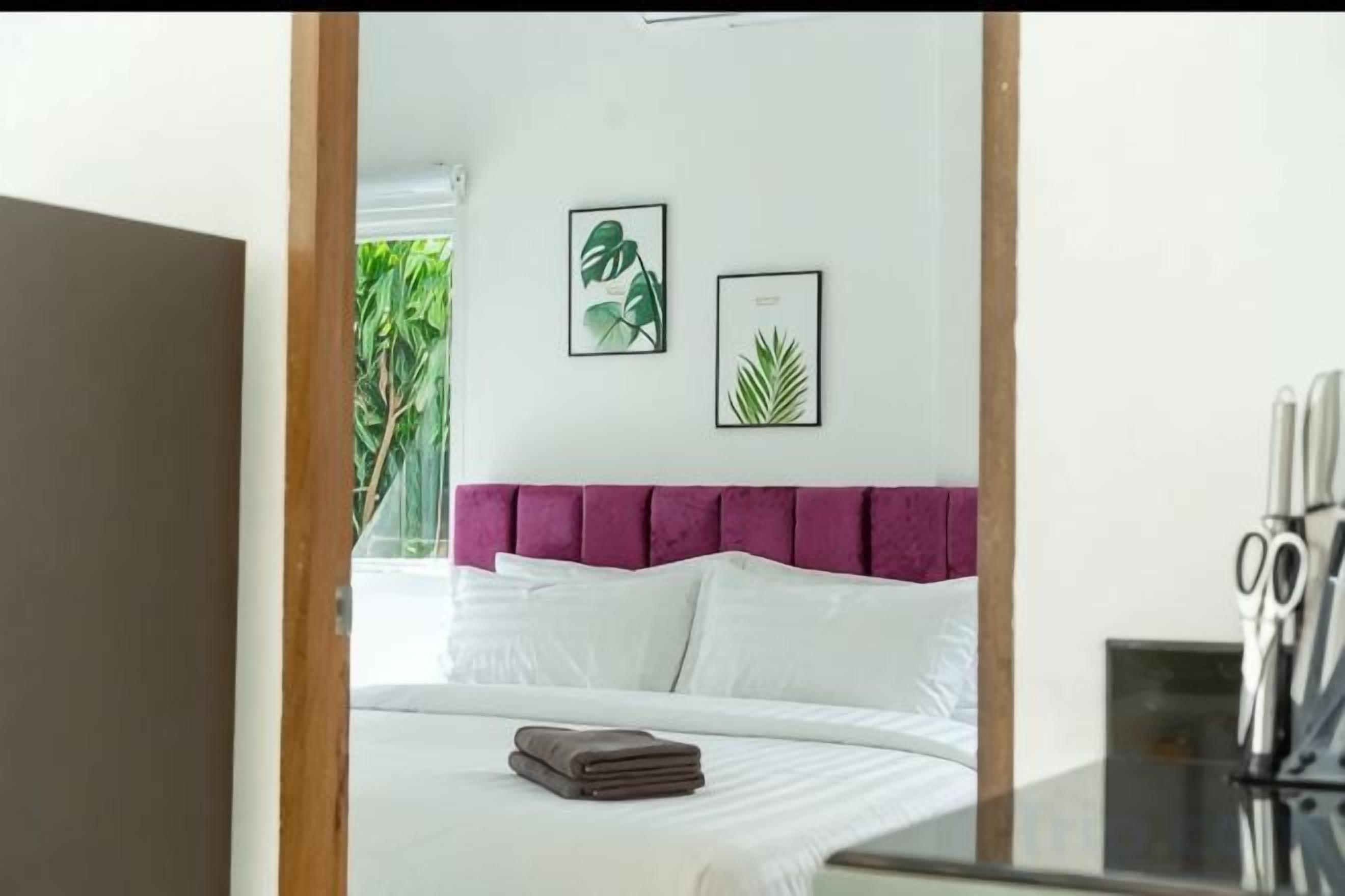 A bedroom with a bed, pillows, a headboard, and two framed pictures on the wall.