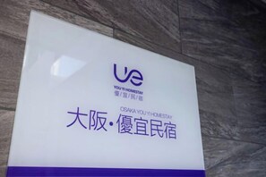 A sign with 'UE' and 'OSAKA YOUYI HOMESTAY' text, indicating a hotel name. - UE HOTEL (Osaka)