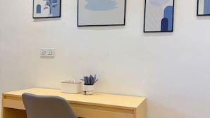 Una habitación con un escritorio, una silla y tres cuadros en la pared.