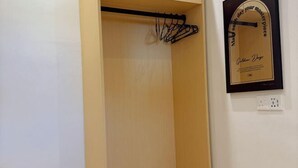 Una habitación con un armario de madera, un perchero negro y un diploma enmarcado en la pared.