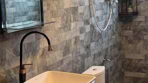 Un baño con lavamanos color crema, grifo negro y una mampara sobre el espejo.