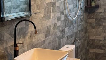 A bathroom with a beige sink, black faucet, and a glass enclosure above the mirror.