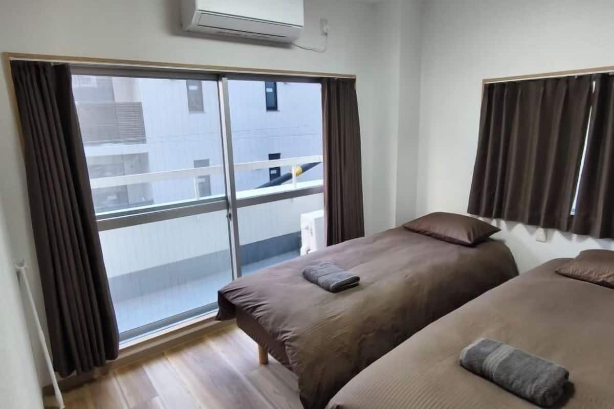 Ein Hotelzimmer mit zwei Betten, einer Schiebetür zu einem Balkon und einer Klimaanlage an der Wand.