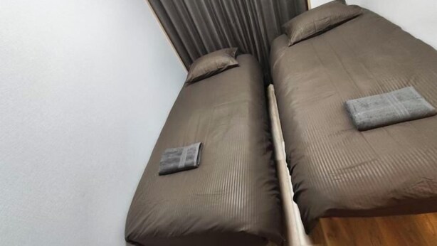 A room with a bed, pillows, and a wooden floor. - Isshuku Ryokan Kotobuki Sanchome (Tokyo)