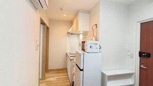 A narrow hallway with a white refrigerator, a microwave, and a sink. - Isshuku Ryokan Kotobuki Sanchome (Tokyo)