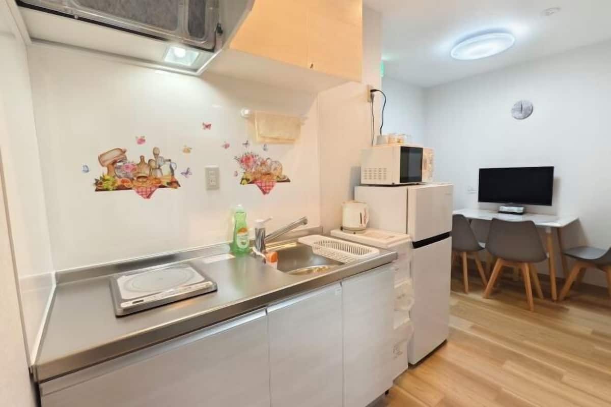 Eine Küchenzeile mit einer Mikrowelle, einem Toaster, einem Spülbecken und einer kleinen Essecke mit Stühlen.