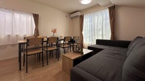 A modern living room with a sofa, dining table, chairs, and a small coffee table. - nestay villa tokyo itabashi (Tokyo)