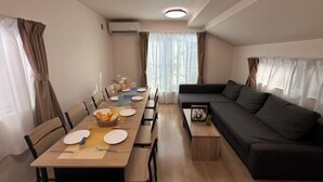 A modern living room with a dining area, a sofa, and a dining table set for four. - nestay villa tokyo itabashi (Tokyo)