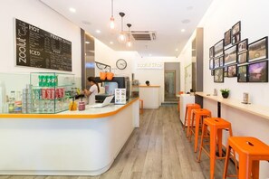 A cafe interior with a counter, stools, and a menu board. - The Hotel Nicecy (Ho Chi Minh City)