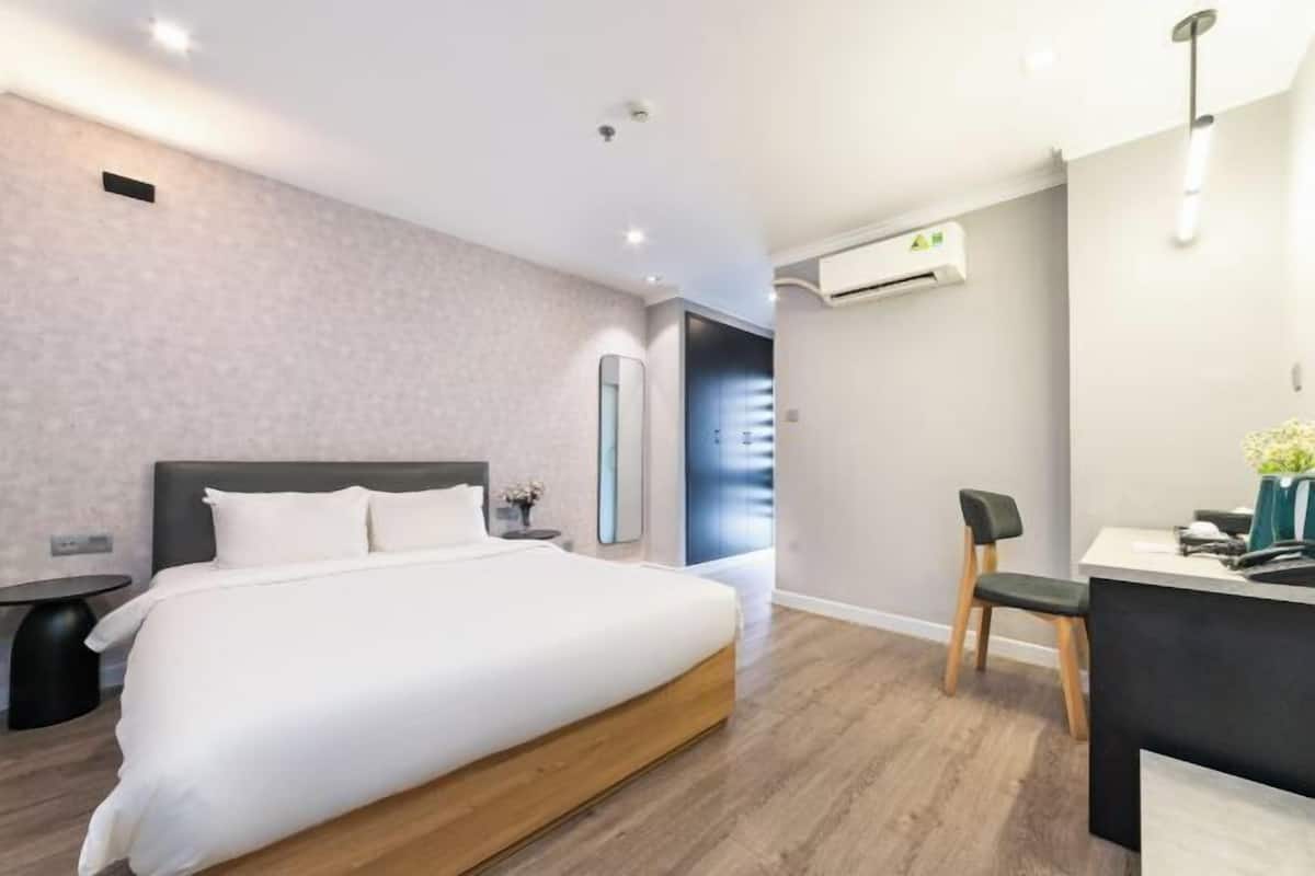 Een moderne hotelkamer met een groot bed, een bureau en een airconditioner.