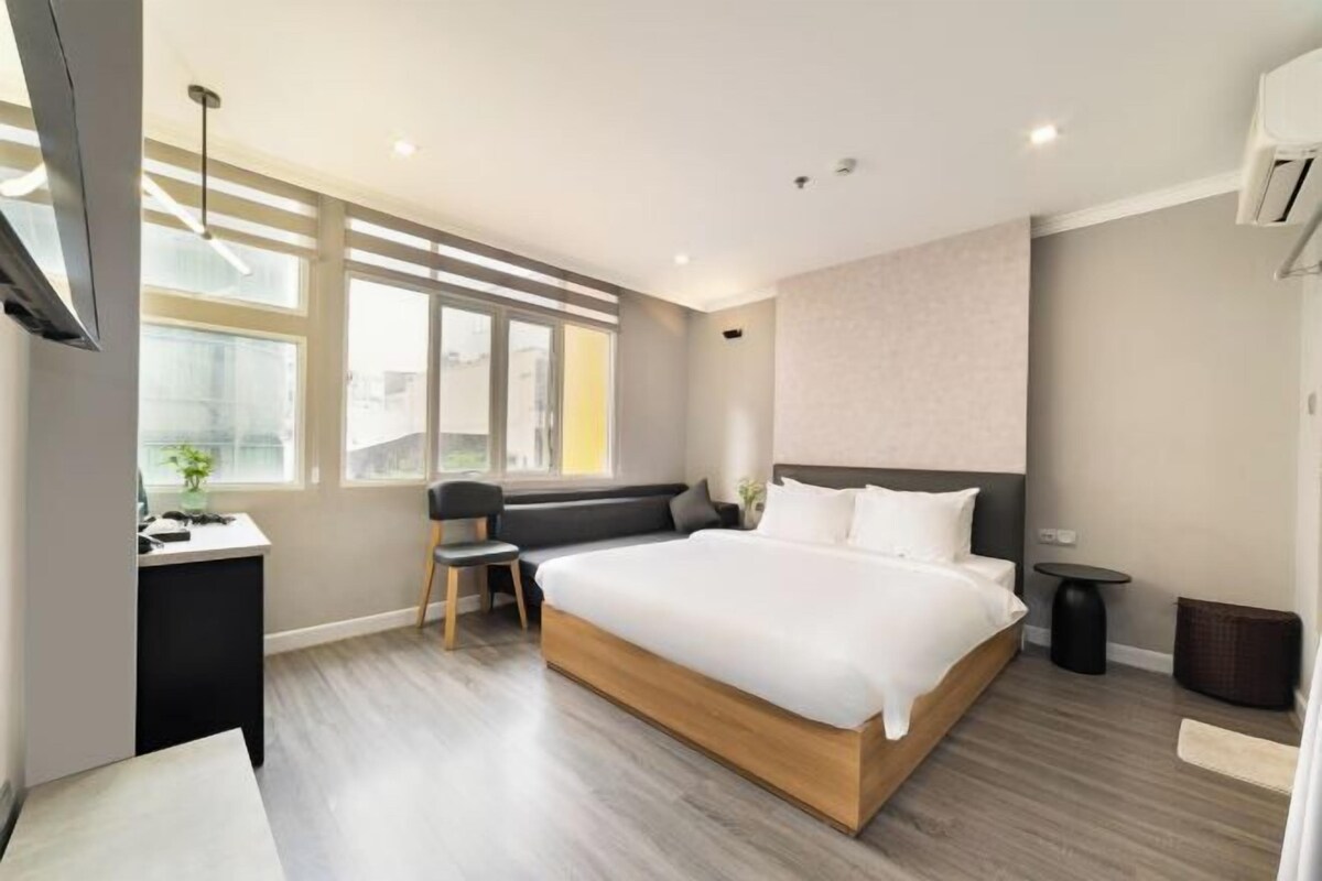 Une chambre d’hôtel moderne équipée d’un grand lit, d’un bureau, d’une chaise et d’une petite table.