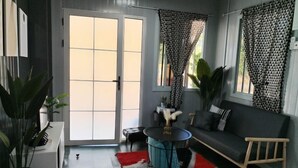 En moderne stue med en grå sofa, et rundt sofabord og en gulvdug i røde og hvide striber.