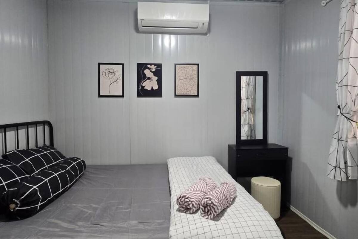 Une chambre à coucher avec un lit, une table de chevet, un miroir et trois tableaux encadrés accrochés au mur.