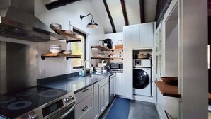 Una cocina moderna con electrodomésticos de acero inoxidable, estantes de madera y lavadora integrada.