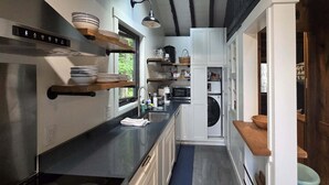 Una cocina moderna con electrodomésticos integrados, estantes de madera y vistas al exterior.