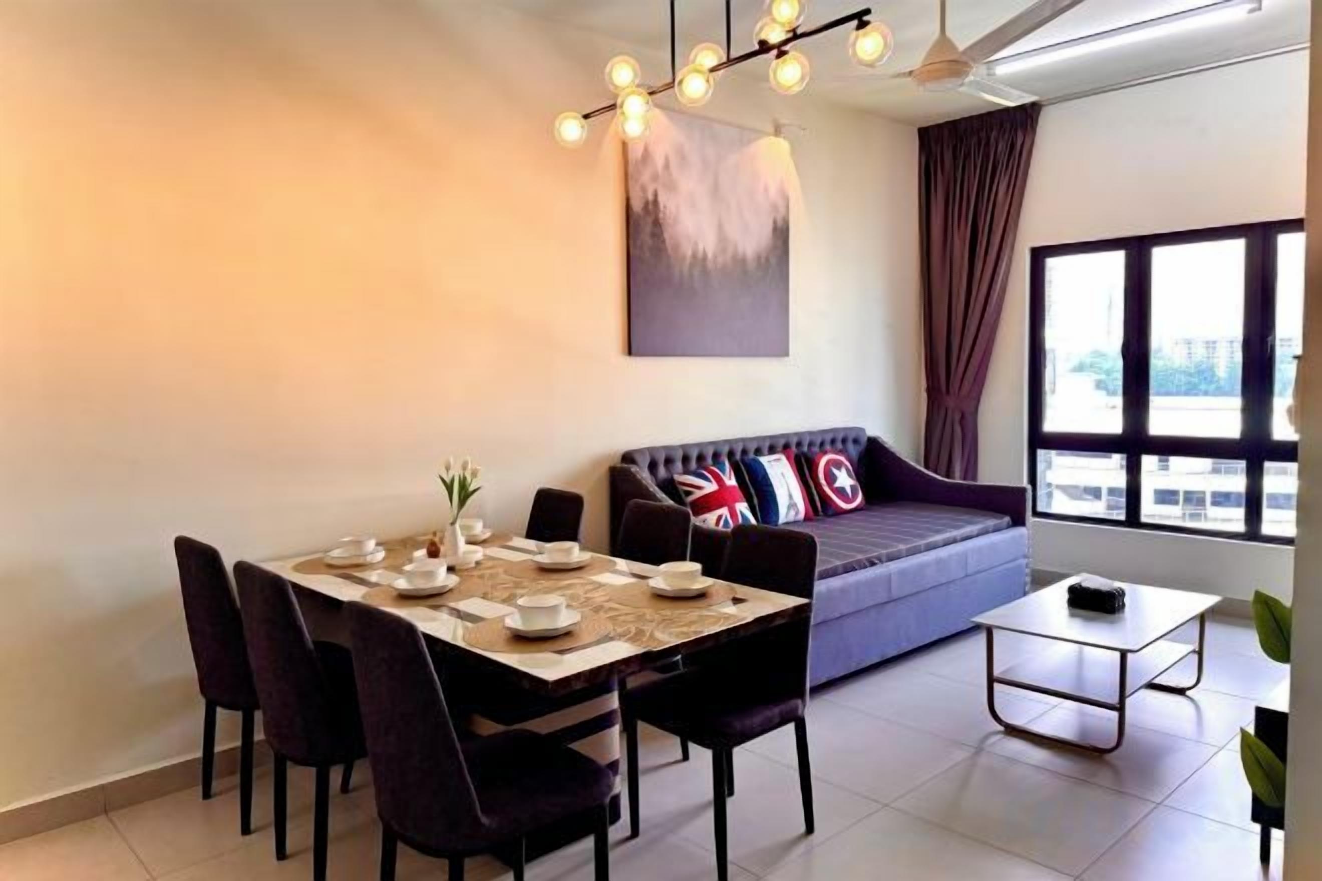 A dining area with a table set for four, a sofa with cushions, a coffee table, and a large window with curtains.