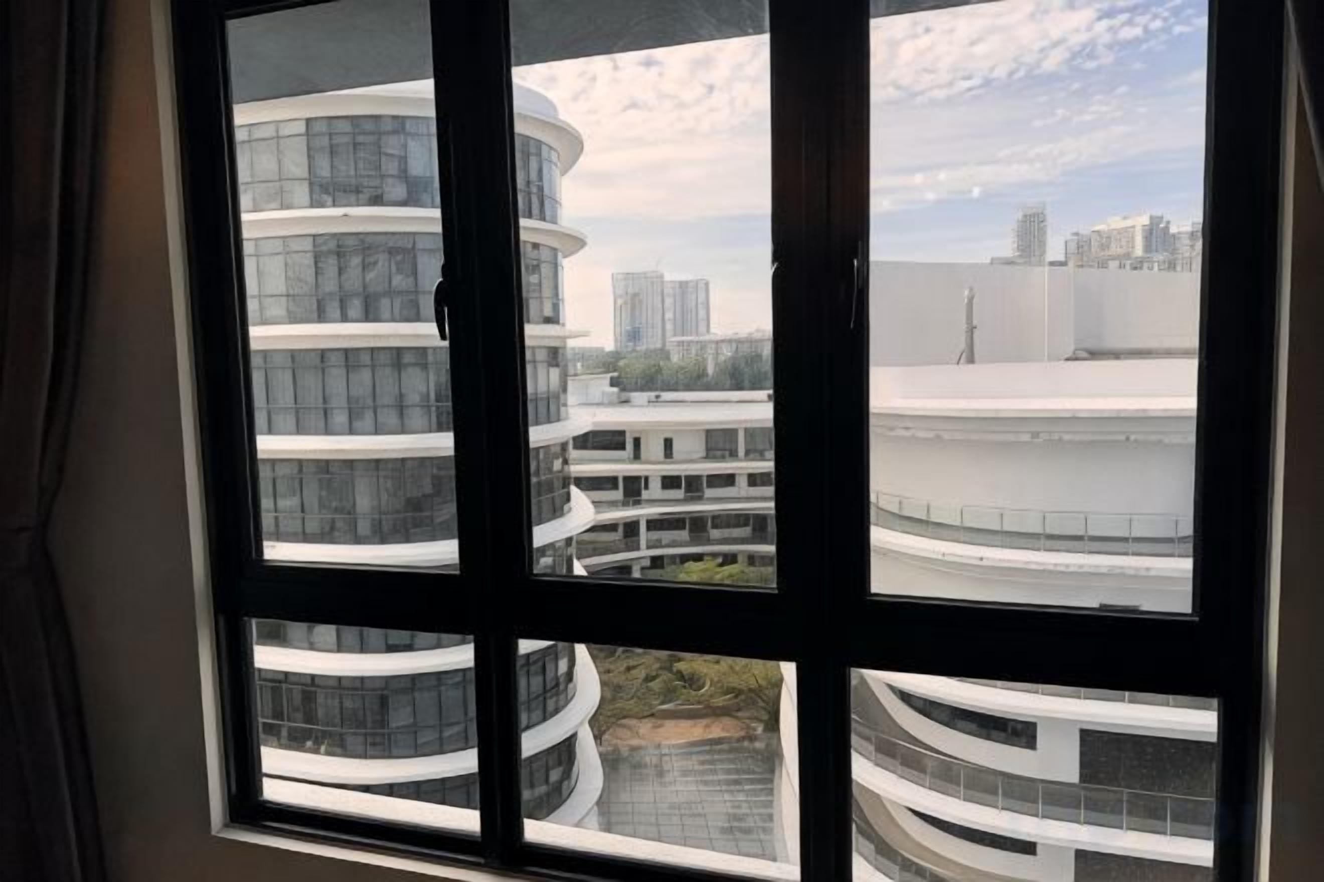 Una ventana con vistas a edificios modernos y una estructura curva.