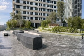 Una terrassa a la teulada amb zones d'estar, vegetació i edificis moderns al fons.