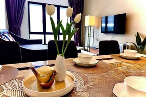 Een eettafel met een vaas witte bloemen, een schaal eten en een dienblad met borden en kopjes.