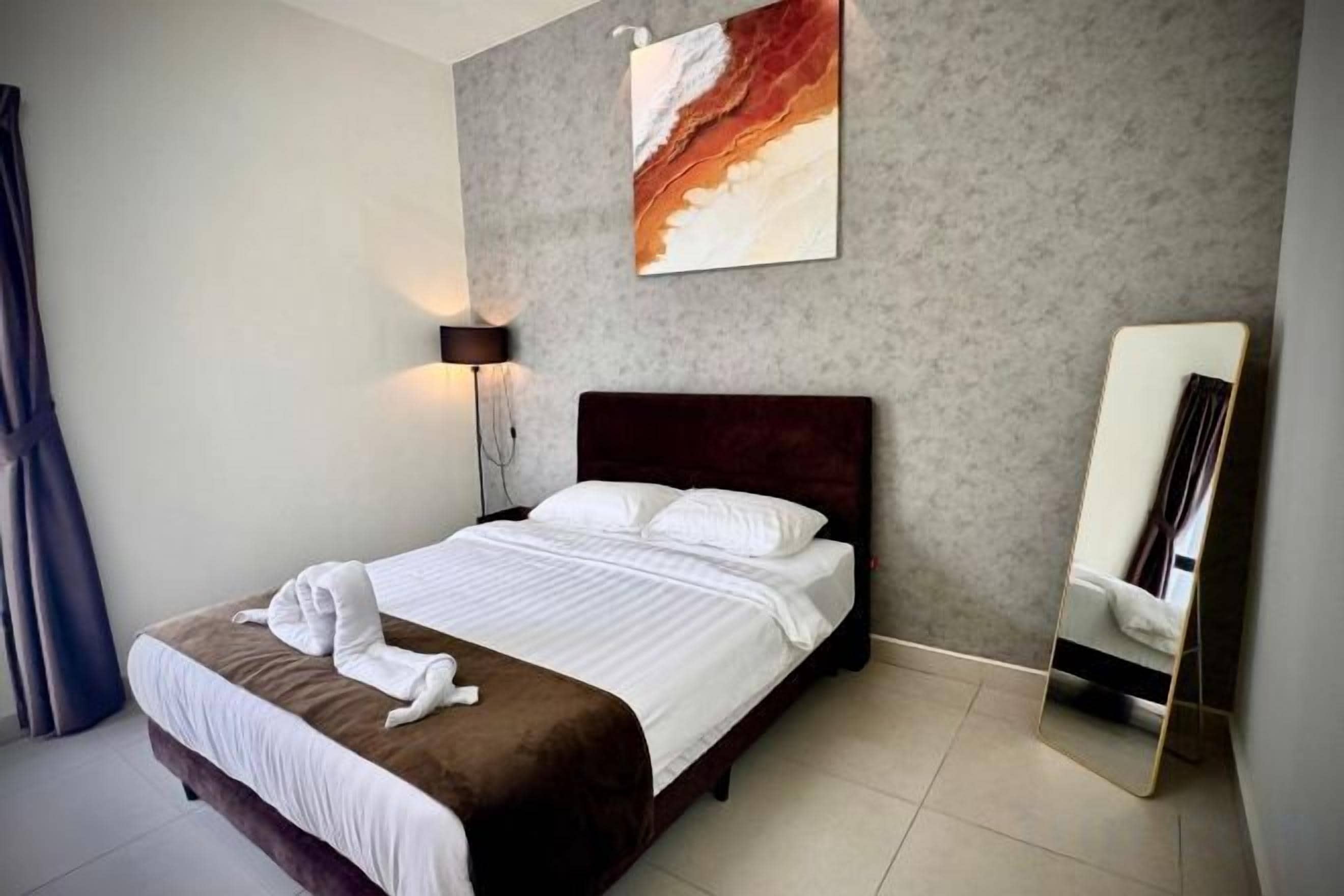 Ein Hotelzimmer mit einem Bett, einer Nachttischlampe, einem Spiegel und einem Bild an der Wand.