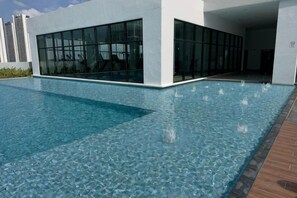 Una piscina junto a un edificio con grandes ventanales.
