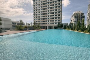 Una piscina con superficie de azulejos, rodeada de edificios modernos, bajo un cielo despejado.