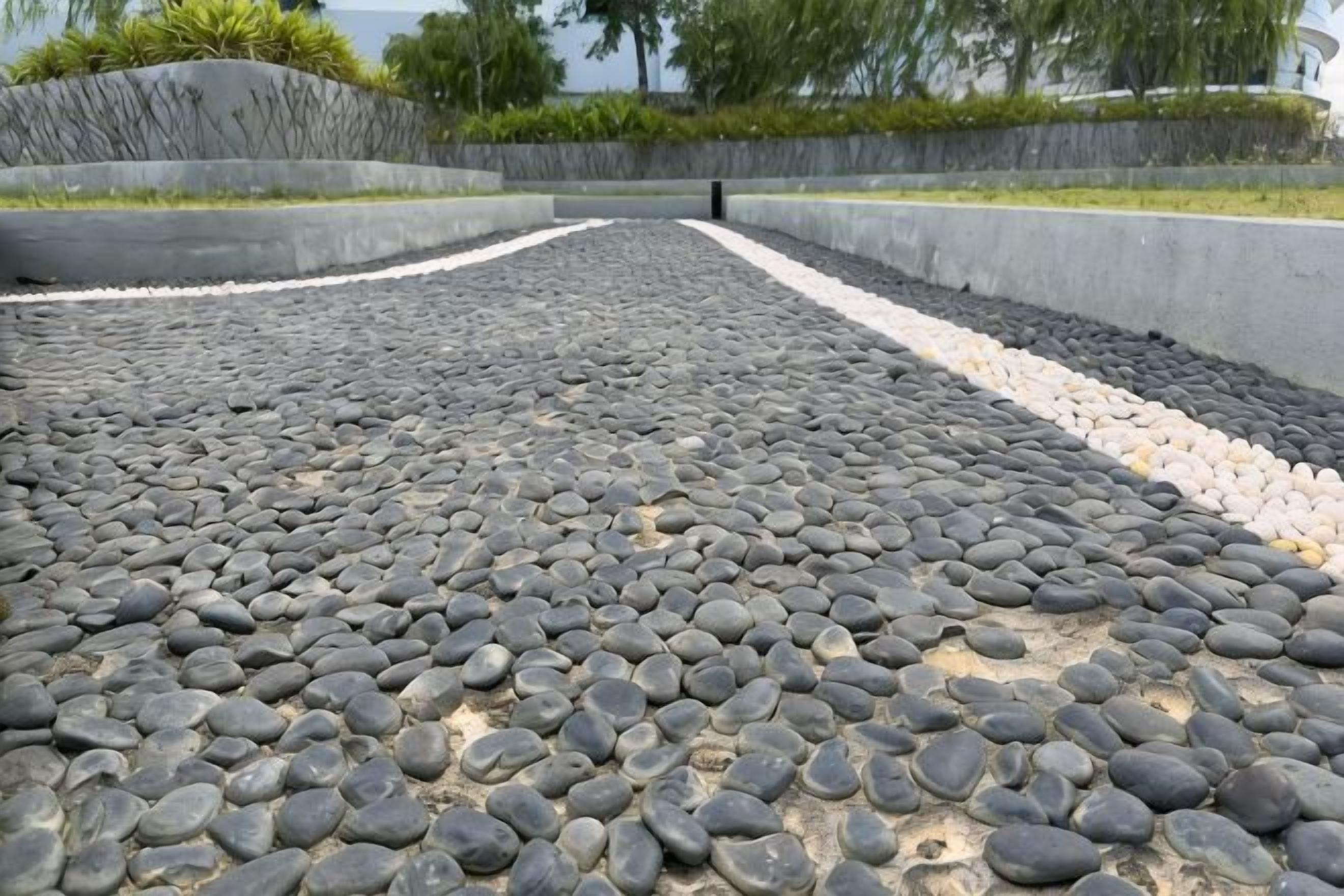 A pathway with a pebble surface leading to a curved wall.