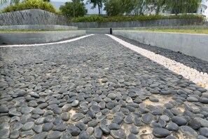 A pathway with a pebble surface leading to a curved wall. - 2R2B Sweet Home Cyberjaya Suites (Cyberjaya)