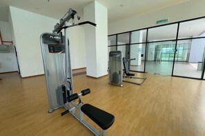 Een fitnessruimte met trainingsapparatuur, een bank en een groot raam.
