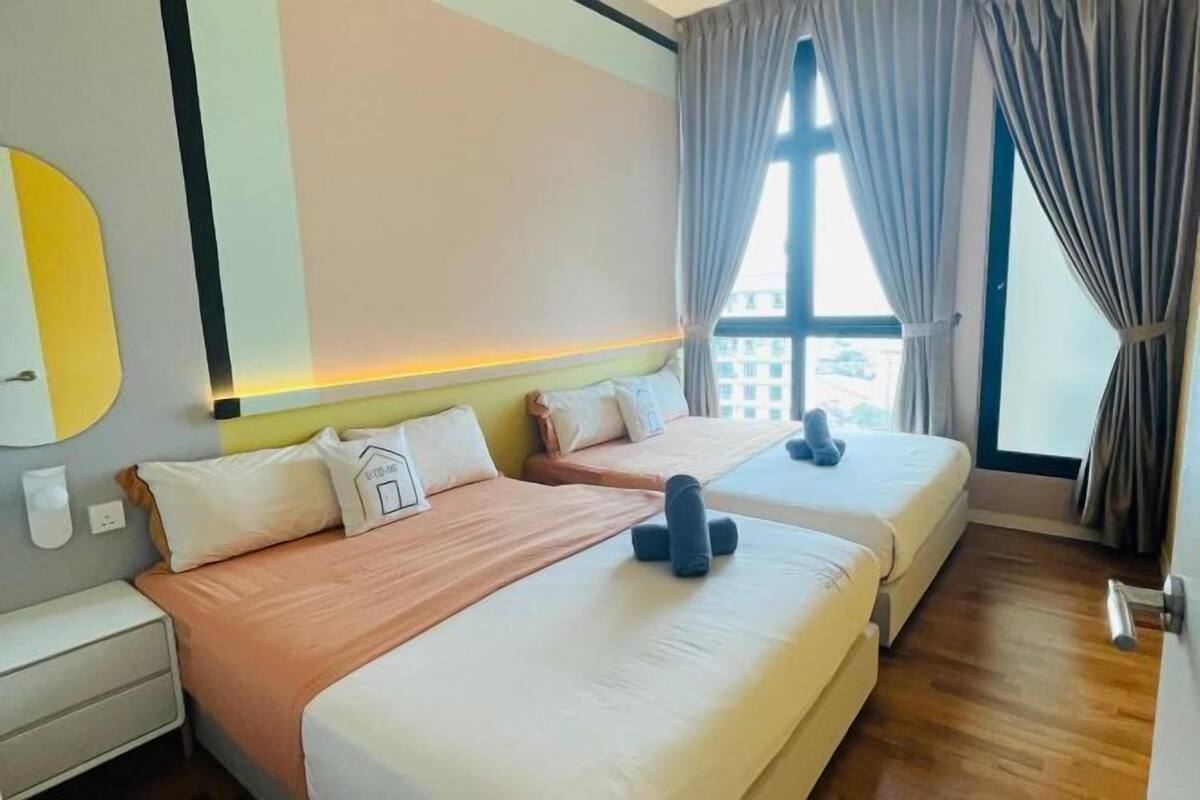 Ein Hotelzimmer mit zwei Betten, einem Nachttisch, einer Wandleuchte und einem Fenster mit Vorhängen.