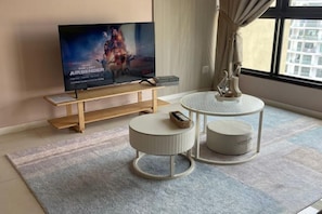 A modern living room with a flat-screen TV, a wooden coffee table, two round side tables, and a large window. - L22-ParadigmMall Residence Skudai JB 3R2B-10pax by UcomeHomestay (Tebrau)