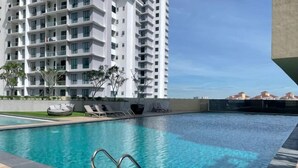 En swimmingpool med liggestole og en skyskraber i baggrunden.