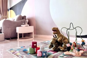Dinosauruslelu matolla, jonka päällä on värikkäitä palikoita ja jonka yläpuolella roikkuu lelu.