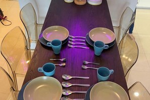 Une table à manger dressée avec des assiettes, des tasses et des couverts.