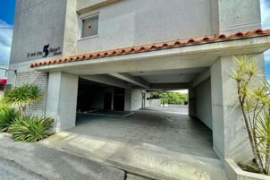 A building entrance with a covered walkway, concrete pillars, and a small window with a heart symbol.