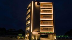 A modern multi-story building with illuminated balconies and a well-lit entrance.