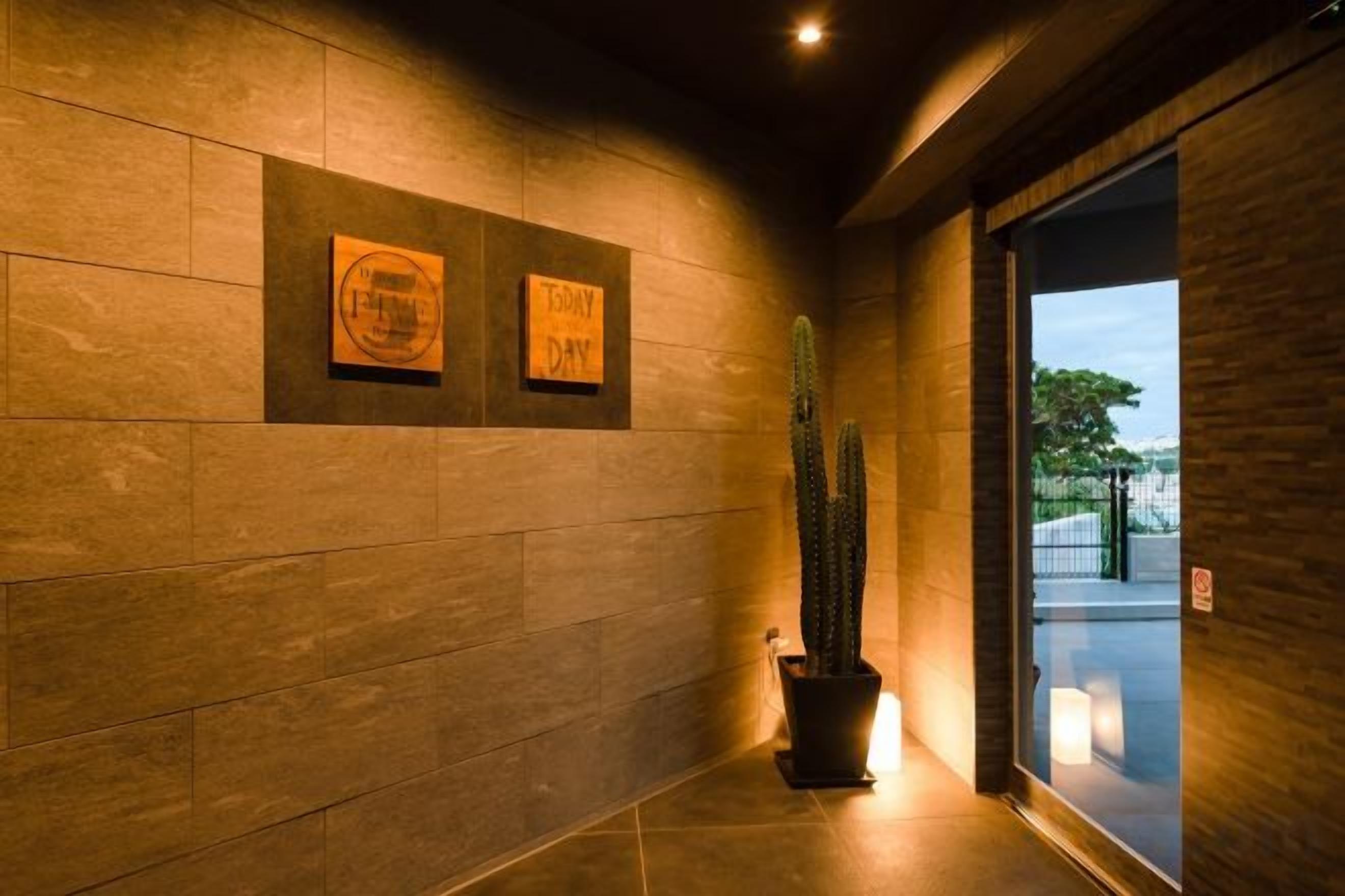 A hallway with a cactus, two framed signs, and a door leading outside.