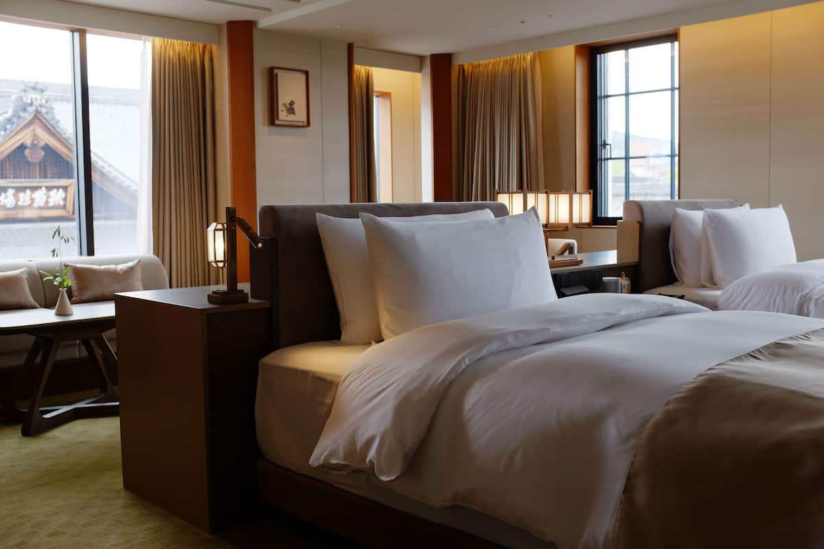 A hotel room with a large bed, a desk, and a view of a traditional building.