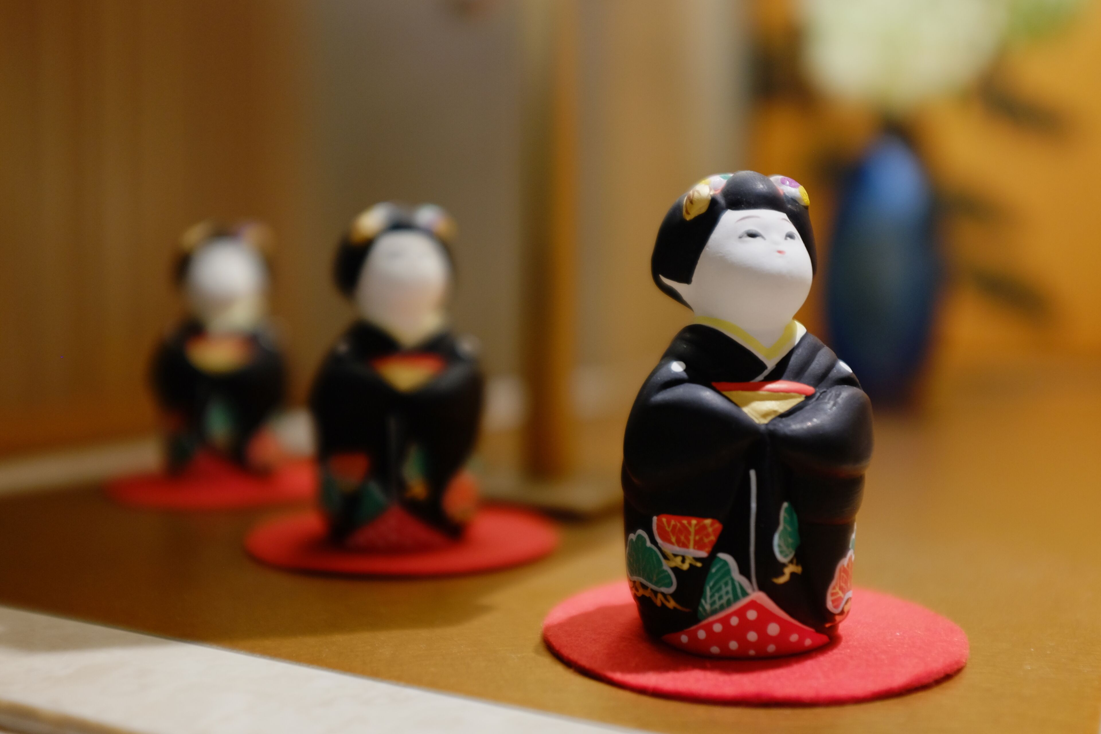 Three traditional Japanese dolls on a wooden surface.