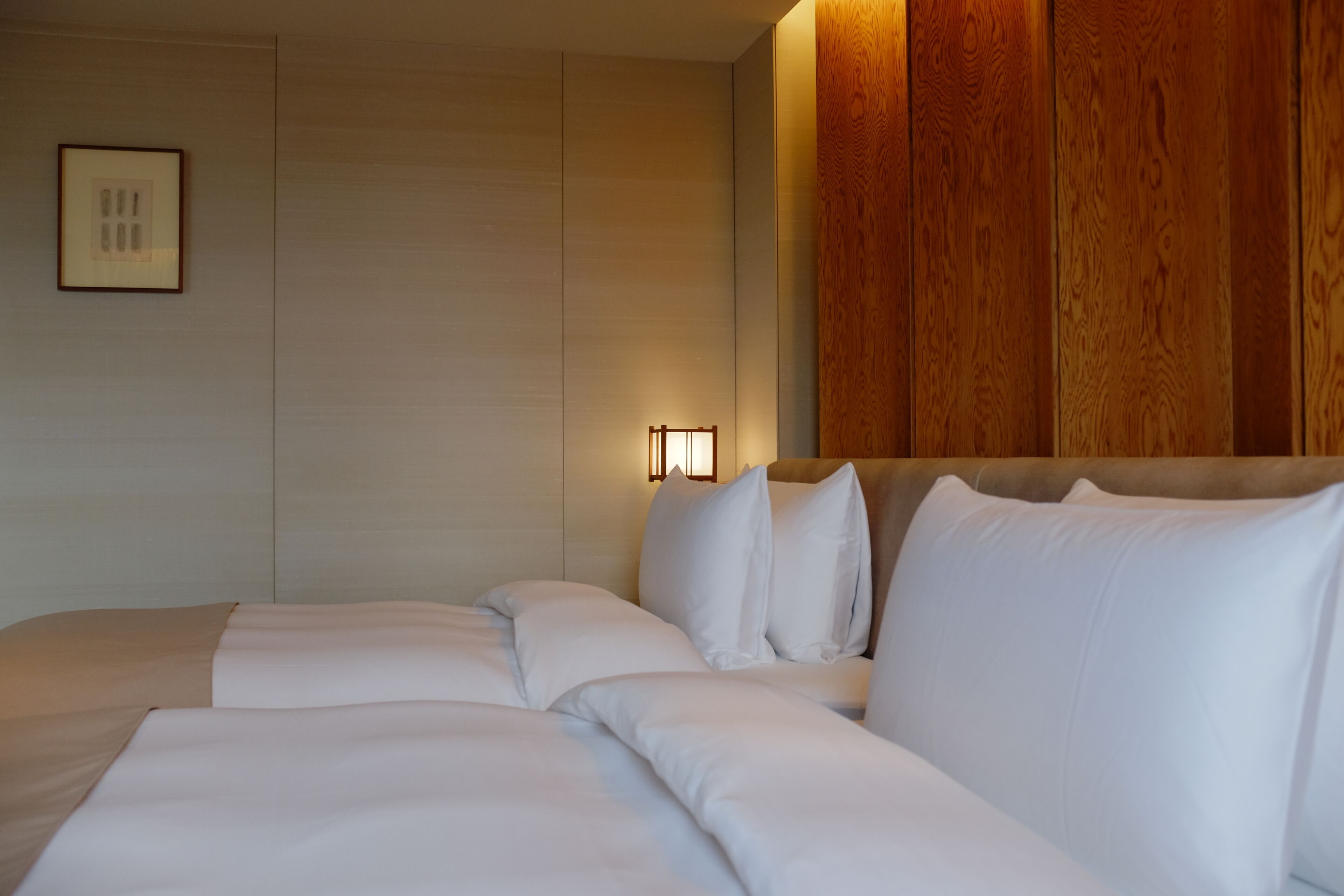 A hotel room with a large bed, a nightstand with a lamp, and a wooden panel wall.