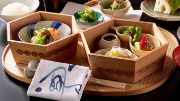 A traditional Japanese meal setup with various dishes in wooden boxes, a bowl of rice, and a napkin with a design.