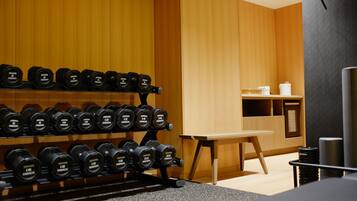 A gym with weightlifting equipment, wooden walls, and a small table with items on it.