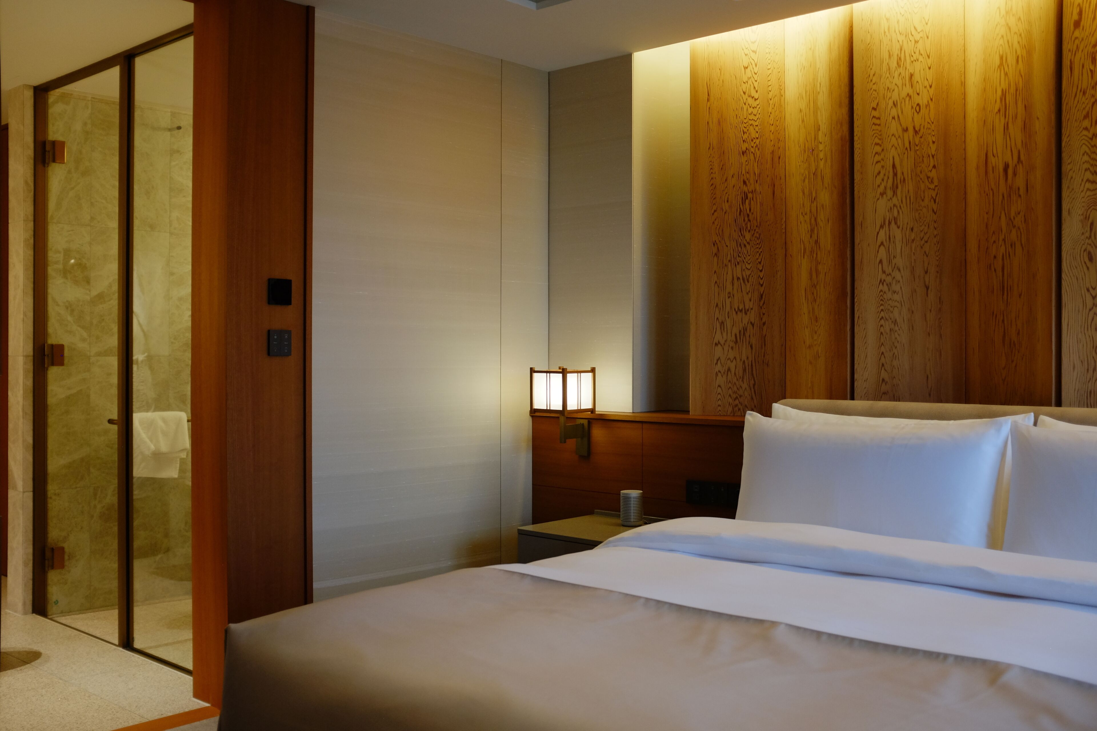 A hotel room with a bed, a nightstand, a lamp, and a sliding door.