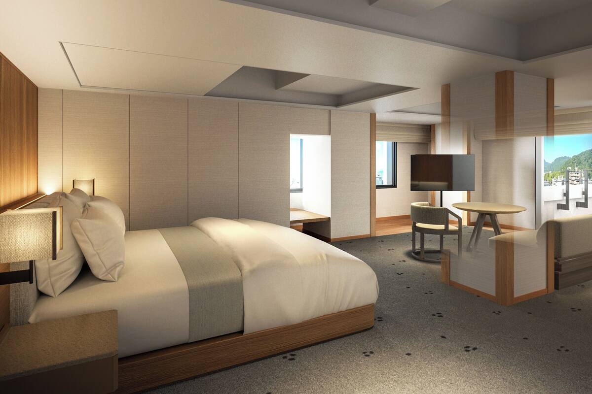 A modern hotel room with a large bed, a desk, a chair, and a TV.